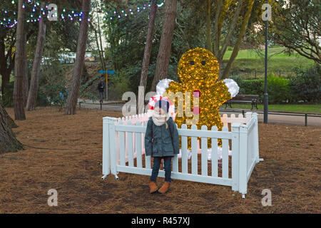 Bournemouth, Dorset, UK. 25th Nov 2018. Bournemouth's first Christmas Tree Wonderland with more than 100 glittering trees and illuminations. Girl standing by gingerbread man amongst the trees in the Lower Gardens. Visitors can follow the trail. Credit: Carolyn Jenkins/Alamy Live News Stock Photo