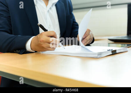 Businessman signing contract paper with pen in office desk. Stock Photo