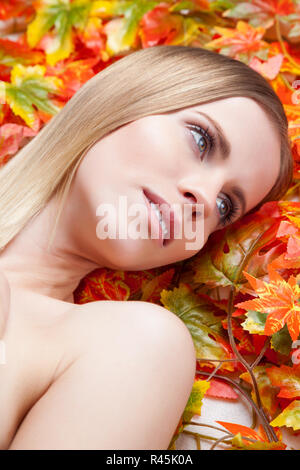 Beautiful young woman lying on leafs Stock Photo