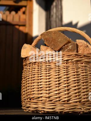 basket with firewood in front of dark background Stock Photo