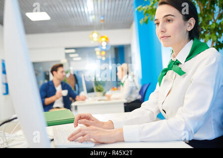 Busy bank representative adding information into computer Stock Photo