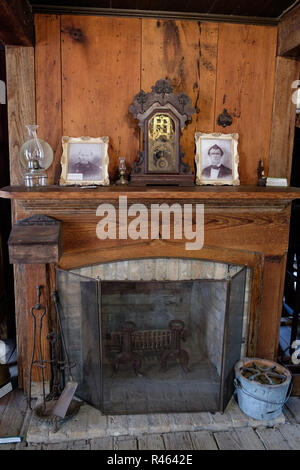 Vintage Texan Home interior with antique fireplace, clock, photos in frames & oil lamps. Chestnut Square Historic Village, McKinney, Texas. Stock Photo