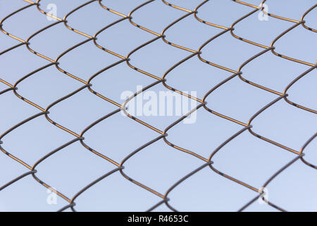 Old and rusty iron net wrapped on blue sky background. Stock Photo