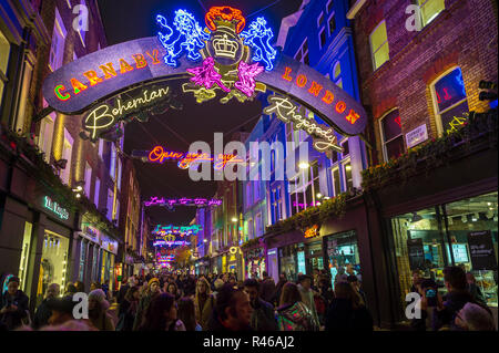 LONDON - NOVEMBER 23, 2018: Black Friday holiday shoppers admire the Bohemian Rhapsody themed Christmas lights decorating Carnaby Street Stock Photo