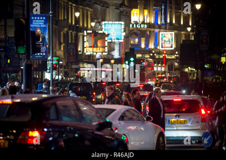 LONDON - DECEMBER 23, 2018: Pedestrians cross a traffic-clogged intersection at Piccadilly Circus in front of the shining lights of West End theatres. Stock Photo