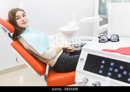 Dental clinic. Reception, examination of the patient. Teeth care. The girl is sitting in the dental chair ready to examine the teeth Stock Photo