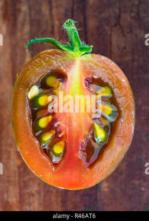 half,red tomato cut open on rustic wooden table Stock Photo