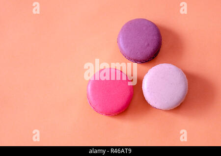 Colorful macaroons are on the orange background,top view. Stock Photo
