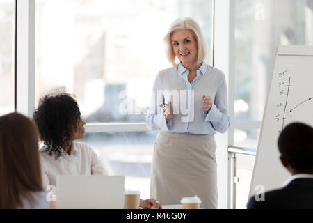 Mature female business coach speaking at team meeting training s Stock Photo