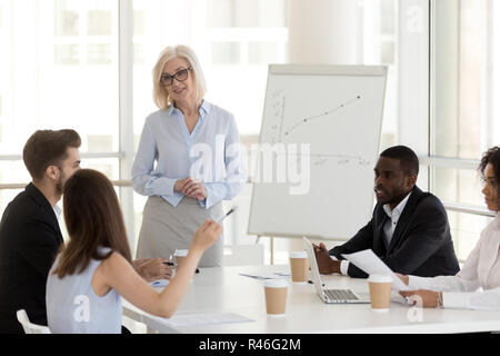 Smiling mature coach communicating with team at business meeting Stock Photo