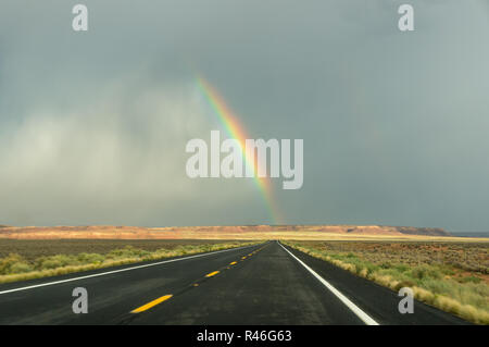 End of a rainbow on a black a road after heavy rain Stock Photo
