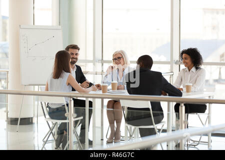 Smiling diverse employees talking at meeting table in conference Stock Photo