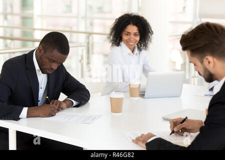 African american and caucasian businessmen signing contracts con Stock Photo
