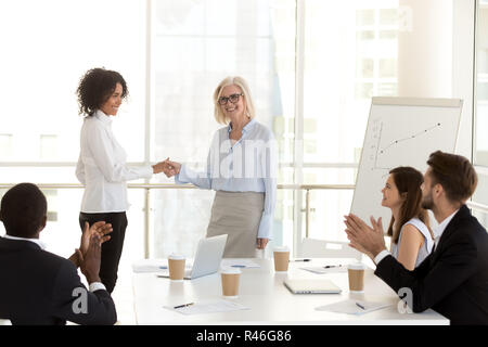Smiling mature boss handshaking african employee congratulating  Stock Photo
