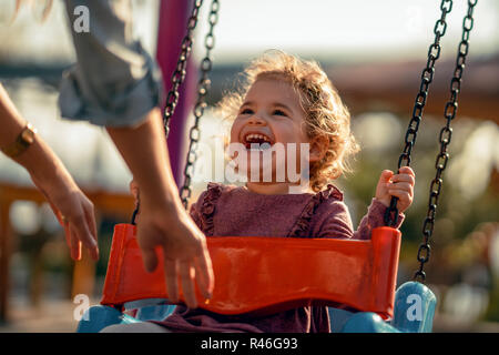 Adorable little girl having fun on a swing. Stock Photo