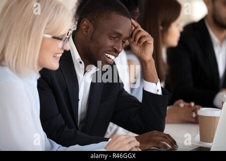 Smiling multi-ethnic coworkers working together in office using  Stock Photo