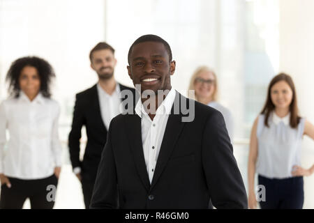 Smiling african corporate leader posing with diverse team in off Stock Photo