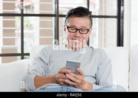 Mature Asian man texting on smartphone Stock Photo