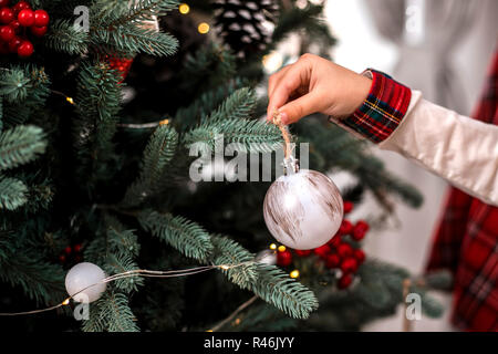 Little child's hand decorating Christmas tree indoors. Stock Photo