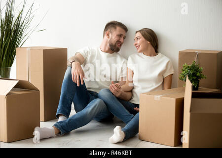 Tired couple sitting leaning back against wall in new apartment Stock Photo
