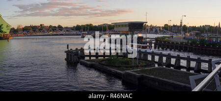 Panoramic view on the sunset over modern bridge across Oosterdok and Nemo Science Center in Amsterdam (The Netherlands). Stock Photo