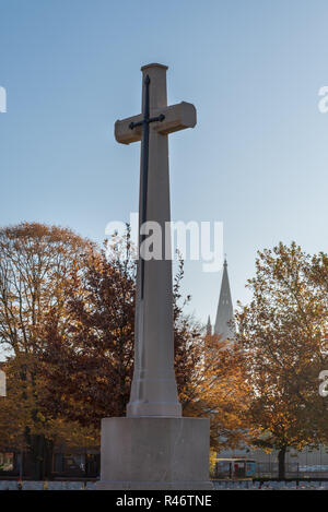 Cross of Sacrifice in Reservoir Cemetery with spire of St Martins Cathedral, Ypres Stock Photo