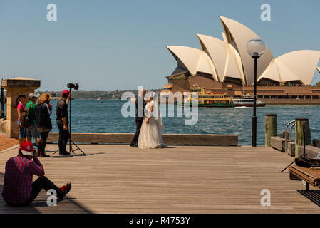 Sydney, Australia--February 16, 2016. Bride and groom pose for wedding pictures using Sydney Harbor and the Opera House as a backdrop. Stock Photo