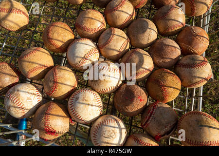 Close up of very used baseball balls in basket with grass background on sunny day. Stock Photo