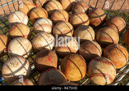 Close up of very used baseball balls in basket with grass background on sunny day. Stock Photo