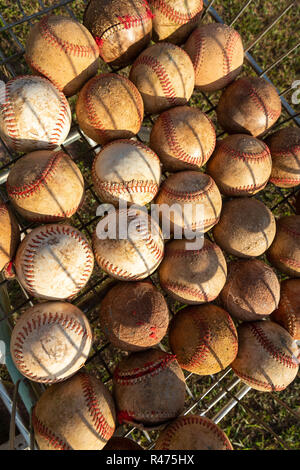 Close up of very used baseball balls in basket with grass background on sunny day. Stock Photo