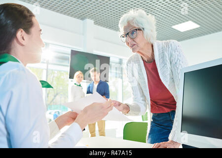 Outraged senior lady speaking loudly in travel agency office Stock Photo