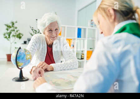 Happy senior customer choosing travel direction with manager Stock Photo