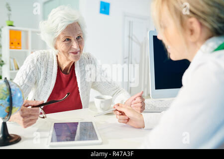 Smiling senior lady choosing travel tour with manager Stock Photo