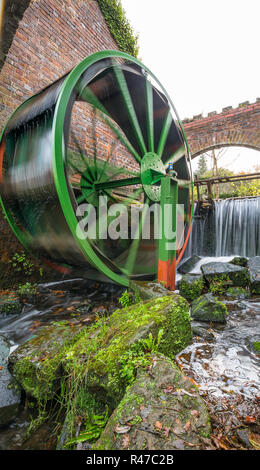 Portrait capture of a moving traditional water mill wheel being supplied by cascading water in background, on a cold autumn morning in Worcestershire. Stock Photo