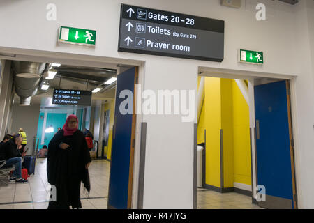 Woman of muslim appearance near sign for prayer room in London Luton Airport, Airport Way, Luton LU2 9LY, UK Stock Photo