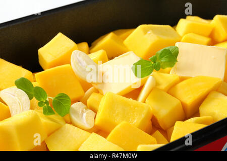 diced pumpkin with butter and garlic in a baking pan Stock Photo