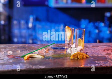 The spilled cocktails with ice cubes on blue color in the bar Stock Photo