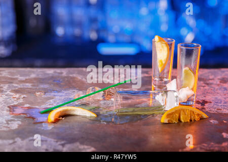 The spilled cocktails with ice cubes on blue color in the bar Stock Photo