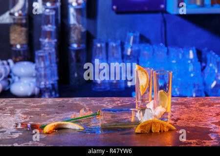 The spilled cocktails with ice cubes on blue color in the bar Stock Photo