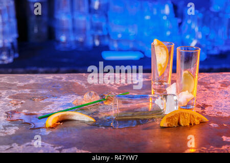 The spilled cocktails with ice cubes on blue color in the bar Stock Photo