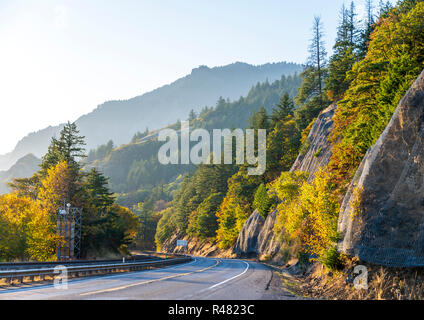 Autumn landscape with turning highway along the Columbia River with a yellow trees on one side and a rocky mountain covered with autumn trees Stock Photo