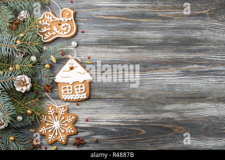 Frame of Gingerbread cookies and Christmas decorations on spruce over wooden background, copy space. Holiday greeting card. Stock Photo