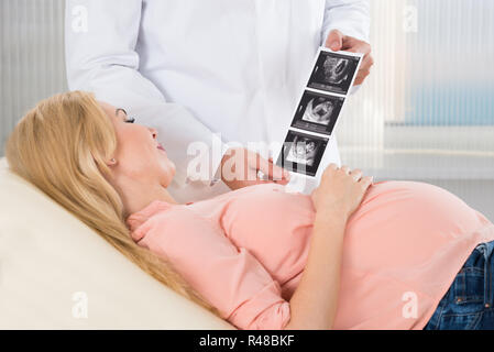 Doctor Showing Ultrasound Scan To Pregnant Woman Stock Photo