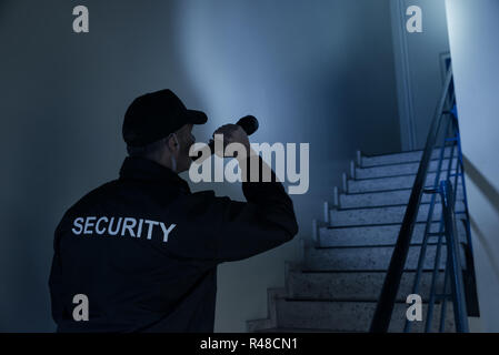 Security Guard Searching On Stairway With Flashlight Stock Photo
