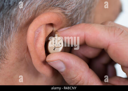 Closeup Of Businessman Inserting Hearing Aid In Ear Stock Photo