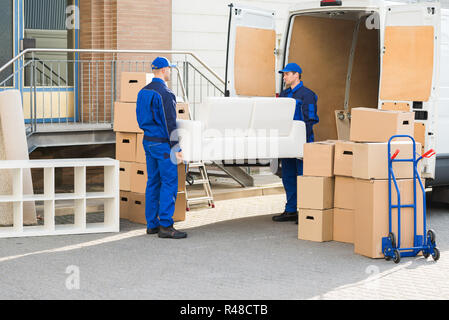 Movers Carrying Sofa Outside Truck On Street Stock Photo