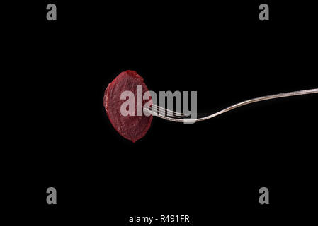 Slice of boiled beets on a fork isolated on a black background Stock Photo