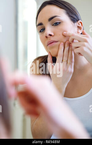 Woman caring of her beautiful skin on the face standing near mirror in the bathroom. Stock Photo