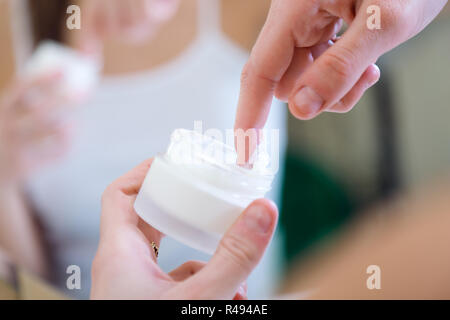 Woman caring of her skin standing near mirror in the bathroom. Stock Photo