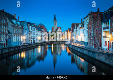 Beautiful panoramic view of famous Spiegelrei canal with famous Poortersloge and Jan van Eyck square in the background illuminated during blue hour at Stock Photo